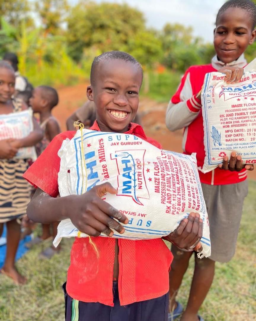 Boys smiling with bags of maize flour from our food program