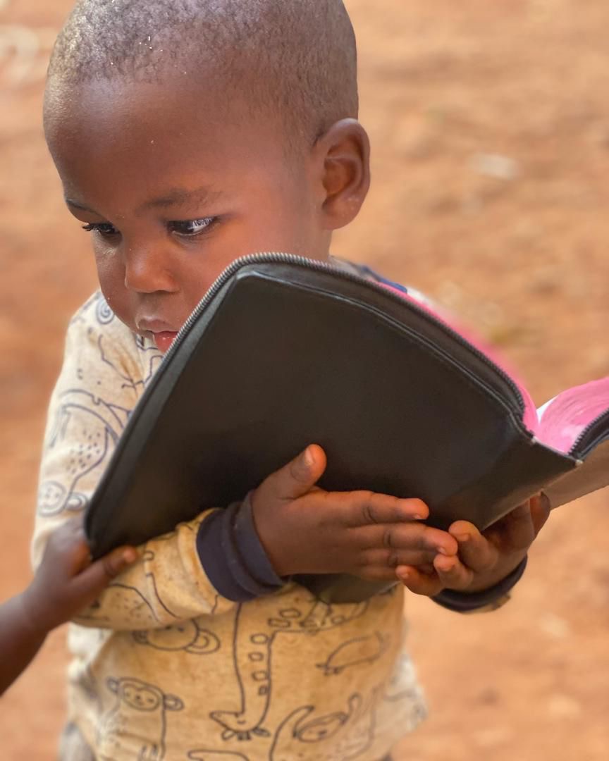 A young child reading from a Bible