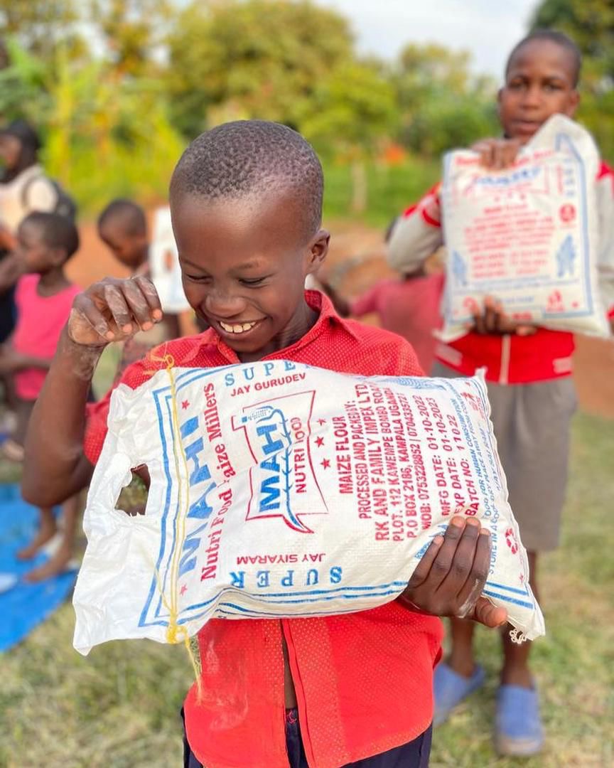 Child smiling with a bag of maize flour from our food program